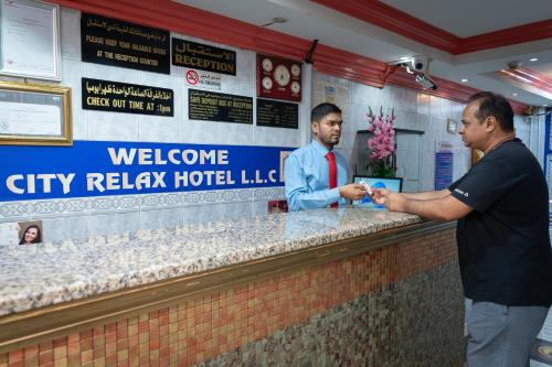 two men are standing at a bar at a hotel at City Relax Hotel in Dubai