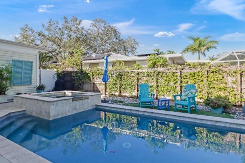 a backyard with a swimming pool and two blue chairs at Coastal Soul House in the heart of Naples in Naples