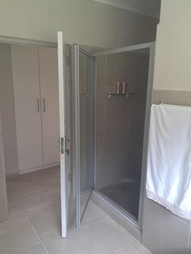 a shower with a glass door in a bathroom at Sea Cottage in Noordhoek