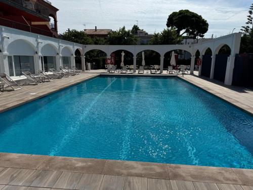 a large blue swimming pool with chairs and tables at Hotel Canal Olímpic in Castelldefels