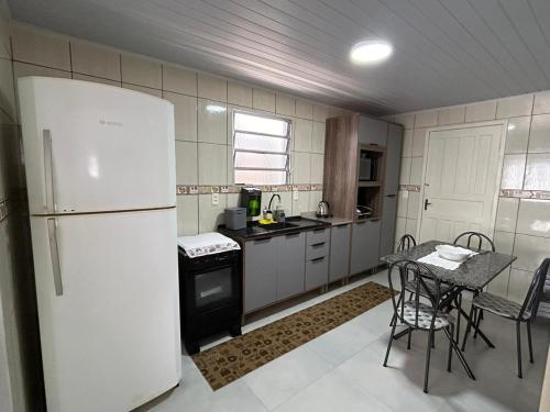 cocina con nevera blanca y mesa con sillas en Casa completa - Governador Celso Ramos à 15min da praia de palmas, en Governador Celso Ramos