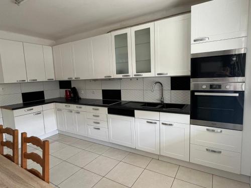 une cuisine blanche avec des armoires et des appareils blancs dans l'établissement Très belle maison, à Sélestat