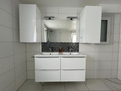 a white kitchen with a sink and a mirror at Très belle maison in Sélestat