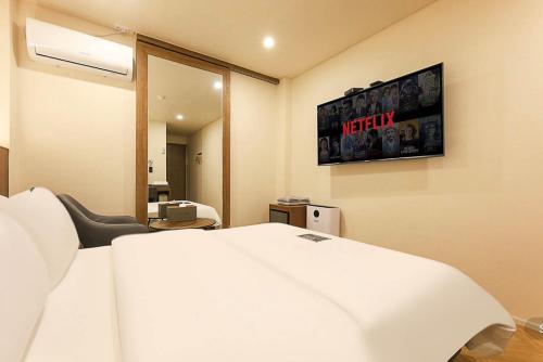 a hotel room with a bed and a television on the wall at Hotel Laglas Asan in Asan