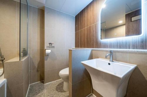 a bathroom with a sink and a toilet and a mirror at Hotel Laglas Asan in Asan