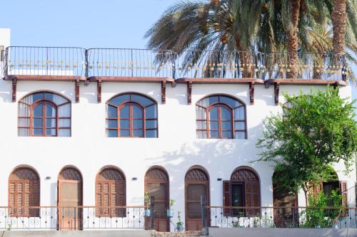 a white building with windows and a palm tree at Eyaru Palace Nile View in Luxor