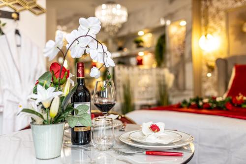 une table avec une bouteille de vin et un vase de fleurs dans l'établissement Le Rubis - Love Room Romantique, à Juvisy-sur-Orge