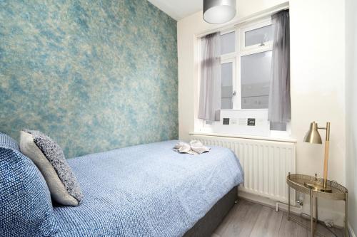 a bedroom with a bed and a window at Large 4 bedroom house with parking available in Golders Green