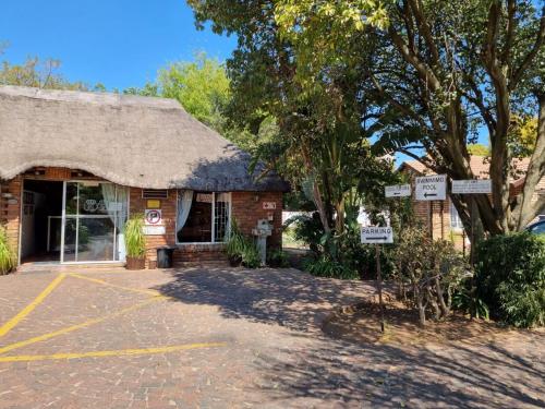 a building with a thatched roof and a parking lot at Airport Inn Bed and Breakfast in Kempton Park