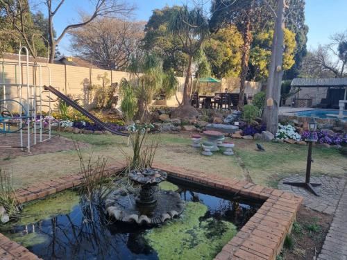 a small pond with a fountain in a yard at Airport Inn Bed and Breakfast in Kempton Park