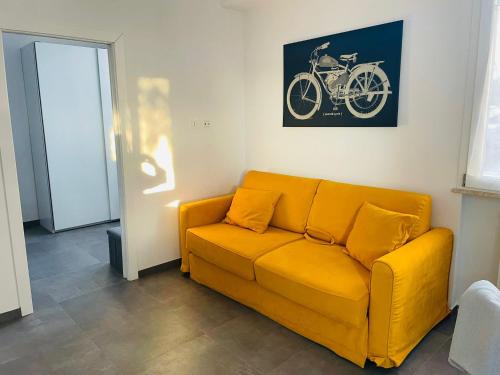 a yellow couch in a room with a picture of a motorcycle on the wall at Casa sul mare con accesso diretto in spiaggia I in Focene