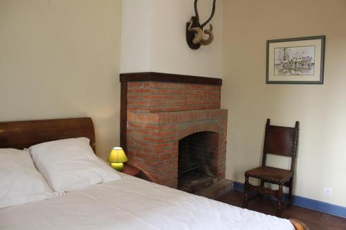 a bedroom with a bed and a brick fireplace at Homestay Château De Saint-Maixant in Saint-Maixant