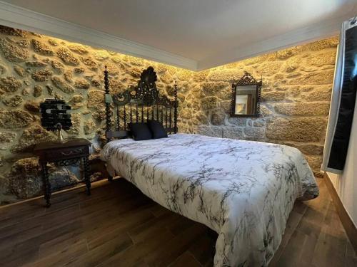 a bedroom with a large bed in a stone wall at Retiro das Águas - Gerês in Terras de Bouro