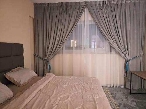 a bedroom with a bed and a window with curtains at The Room of Dream in Ajman
