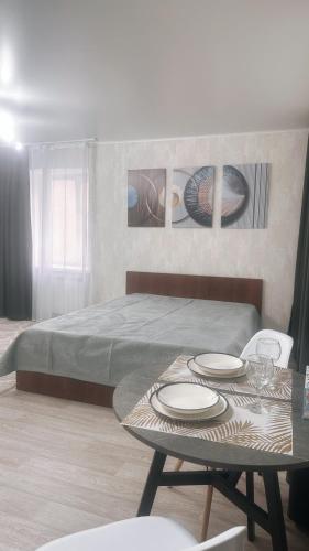 a room with a bed and a table with plates on it at Центр Гоголя 78 in Kostanay