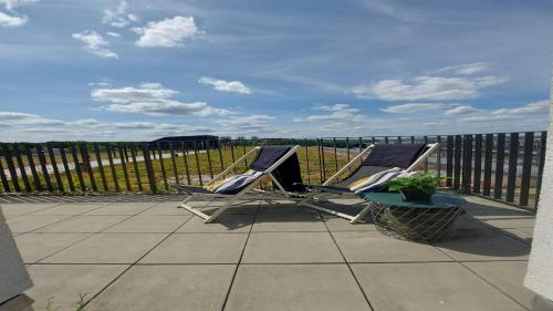 two lounge chairs on a patio with a fence at Holiday Inn - the niu, Sparrow Regensburg by IHG in Regensburg