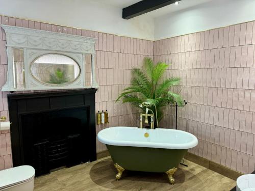 a bathroom with a tub and a palm tree in it at Secret Garden House - 7 bed Manor House with Hot Tub and Magical walled Gardens in Leyburn
