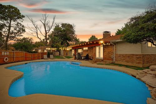 a large blue swimming pool in front of a house at 3-BD Backyard Oasis w Pool Patio Firepit in Irving