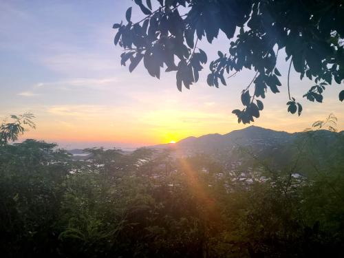 a sunset in the mountains with the sun setting on the horizon at Boundless Bliss Hotel in St Thomas