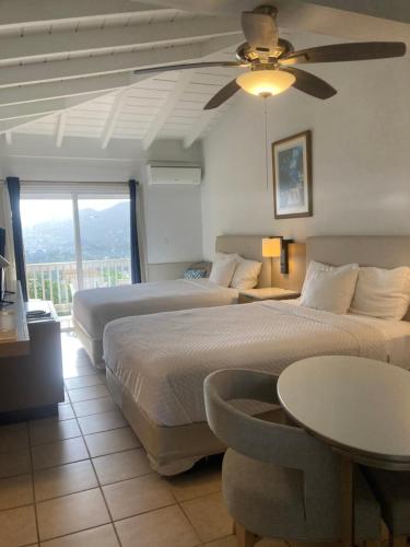 a bedroom with two beds and a ceiling fan at Boundless Bliss Hotel in St Thomas