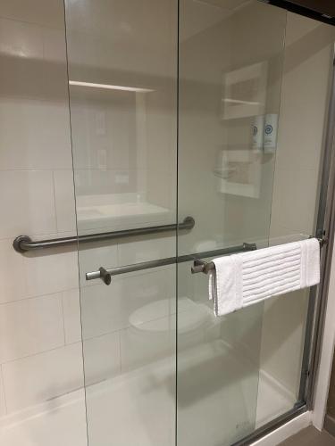 a glass shower door in a bathroom with a towel at Comfort Suites Sawgrass in Tamarac