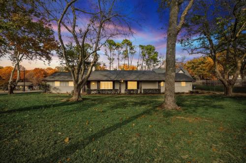 a white house with trees in the yard at Your Rustic Retreat w Backyard Oasis Pool Patio in Keller