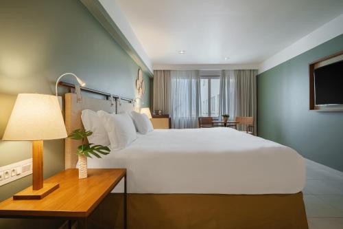 a bedroom with a large white bed and a table with a lamp at Grand Mercure Rio de Janeiro Copacabana in Rio de Janeiro