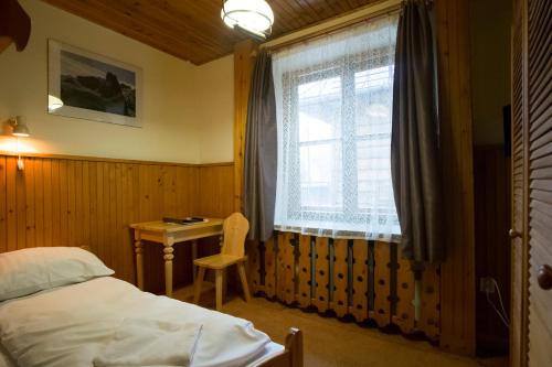 a bedroom with a bed and a desk and a window at Willa Orla in Zakopane