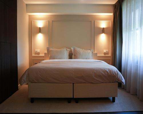 a bedroom with a large bed with white sheets and pillows at The Lodge Bed & Wellness Oisterwijk Sauna, Jacuzzi, Luxury in Moergestel