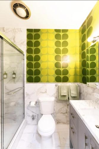 a bathroom with a toilet and green and yellow walls at The Green Room: 70s Groove Themed Studio in New York