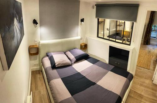 une petite chambre avec un lit et un miroir dans l'établissement Appartement Cosy entre le Bon Marché et Saint Germain Paris 7, à Paris