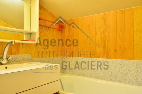 La salle de bains est pourvue d'un lavabo et d'une baignoire avec un panneau mural. dans l'établissement Résidence LES ROCHES - 4 Pièces pour 8 Personnes MAE-9794, à Aime La Plagne