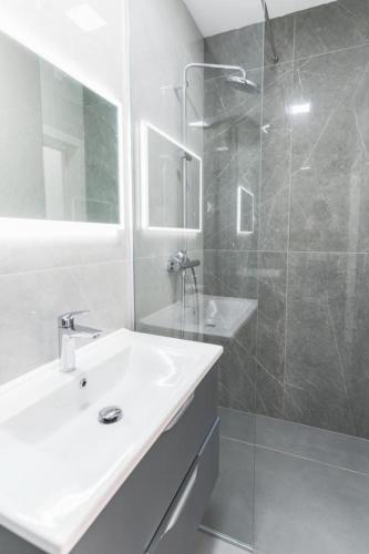 a white bathroom with a sink and a shower at Apartman Dino in Split
