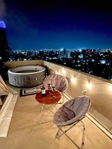 a balcony with two chairs and a table and a bath tub at Glamping con jacuzzi en piso 15, único en Gdl, vistas espectactaculares in Guadalajara