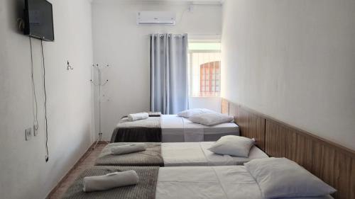 two beds in a small room with a window at Pousada Jesus Misericordioso in Aparecida