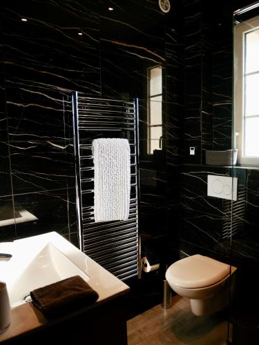 La salle de bains noire est pourvue de toilettes et d'un lavabo. dans l'établissement Deauville Prestige - Chic, Confort & Tout à Pied, à Deauville