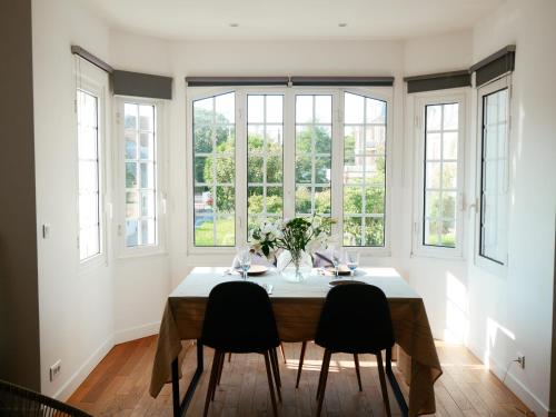 une salle à manger avec une table, des chaises et des fenêtres dans l'établissement Deauville Prestige - Chic, Confort & Tout à Pied, à Deauville