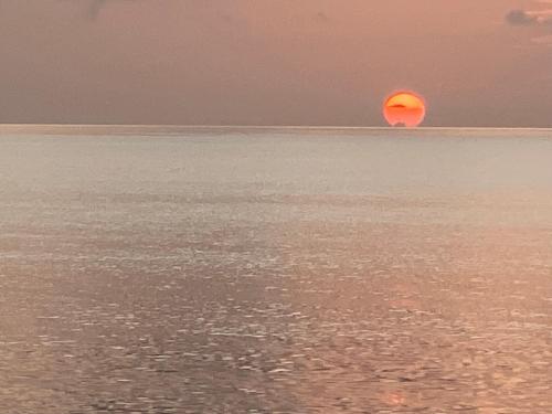 an orange sun in the middle of the ocean at Elegante Apartamento A 100 mts la playa de los Minos RSJ in Río San Juan