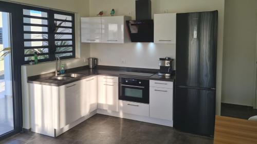 een keuken met witte kasten en een zwarte koelkast bij Villa Cabana Mambo Beach in Willemstad