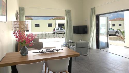 een eetkamer met een tafel, stoelen en een televisie bij Villa Cabana Mambo Beach in Willemstad