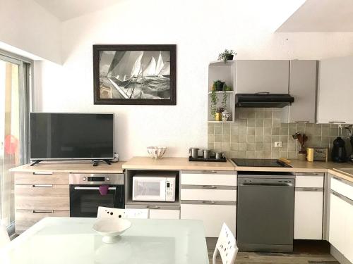 Il comprend une cuisine avec une table et une télévision murale. dans l'établissement Le SAYULA, à Bandol