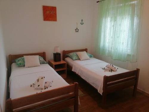 two beds in a room with green curtains at Apartman Volarevic in Donji Karin