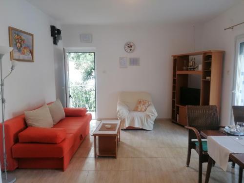 een woonkamer met een rode bank en een tafel bij Apartman Volarevic in Donji Karin