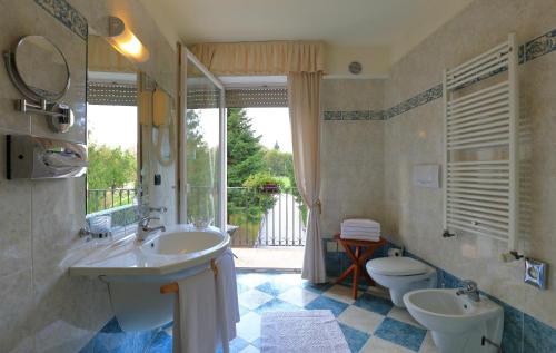 a bathroom with a sink and a toilet and a window at Hotel Lilla' in Terlago