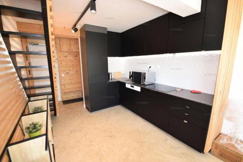 une cuisine avec des armoires noires et un comptoir dans l'établissement Résidence Aime 2000 - 4 Pièces 6 pers. PLAGNE AIME 2000 MAE-4841, à La Plagne Tarentaise