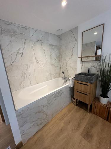 a bathroom with a tub and a sink and a mirror at La Cour des Princesses in Deauville