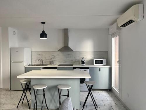 une cuisine avec un comptoir blanc et des tabourets dans l'établissement Neuf et cosy, 6ème Marseille, à Marseille