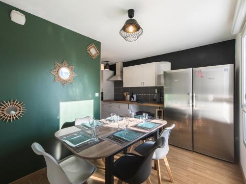 une cuisine avec une table avec des chaises et un réfrigérateur dans l'établissement Le Logis Madeleine - Maison Cosy, à Saint-Pierre-des-Corps