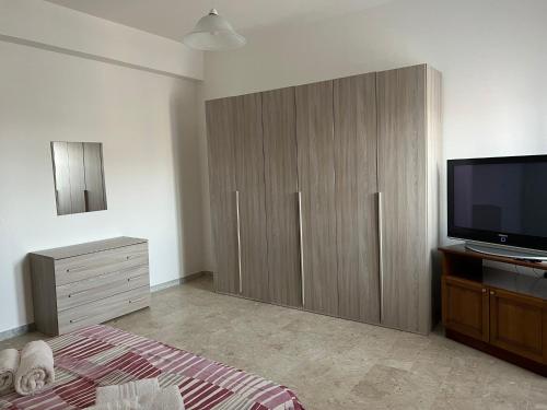 a bedroom with a tv and a large wooden cabinet at Casa Maria in Locri