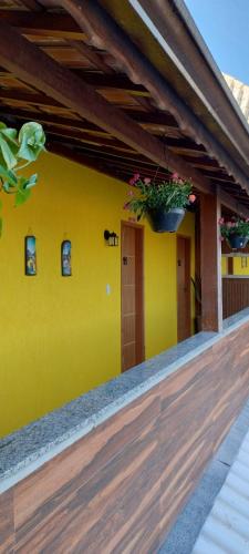 a yellow house with a potted plant on it at Hospedagem Encantos da Serra in Itatiaia